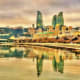 Baku skyline with Flame Towers reflected in Caspian Sea, TV tower and waterfront buildings at sunset